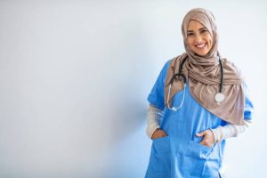 Cheerful young Muslim female nurse portrait, standing inside hospital. Arab female doctor posing and smiling isolated on a white background. Arab nurse woman wearing hijab over isolated background